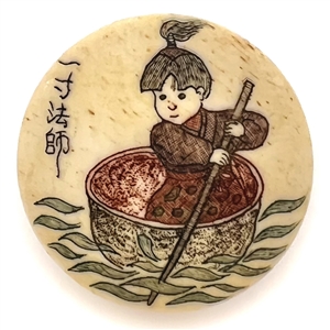 Incised and inked natural material button an Asian child in a small boat.