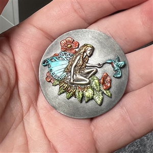Battersea tinted pewter show favor button of a fairy feeding a hummingbird.