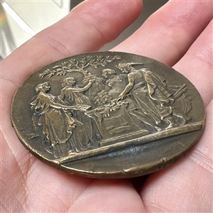 Heavy metal button of robed figures gathered around table under a tree.